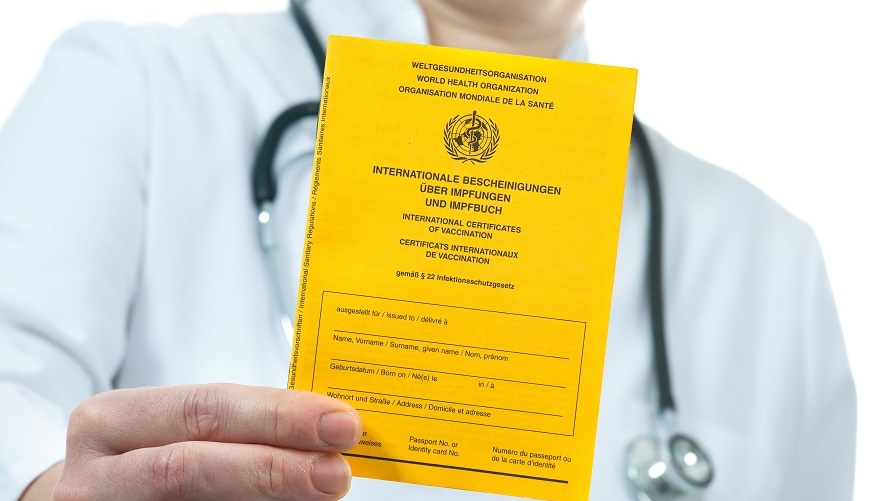 Impfpass. Ein Arzt hält einen gelben Impfpass in der Hand.